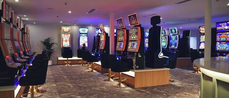 A gaming area with multiple slot machines and a row of massage chairs.