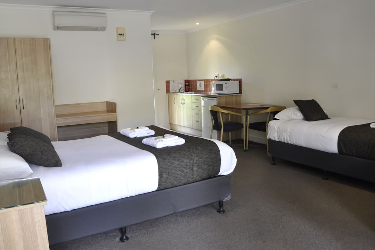 Habitació d'hotel amb dos llits, una cuineta petita i un escriptori.