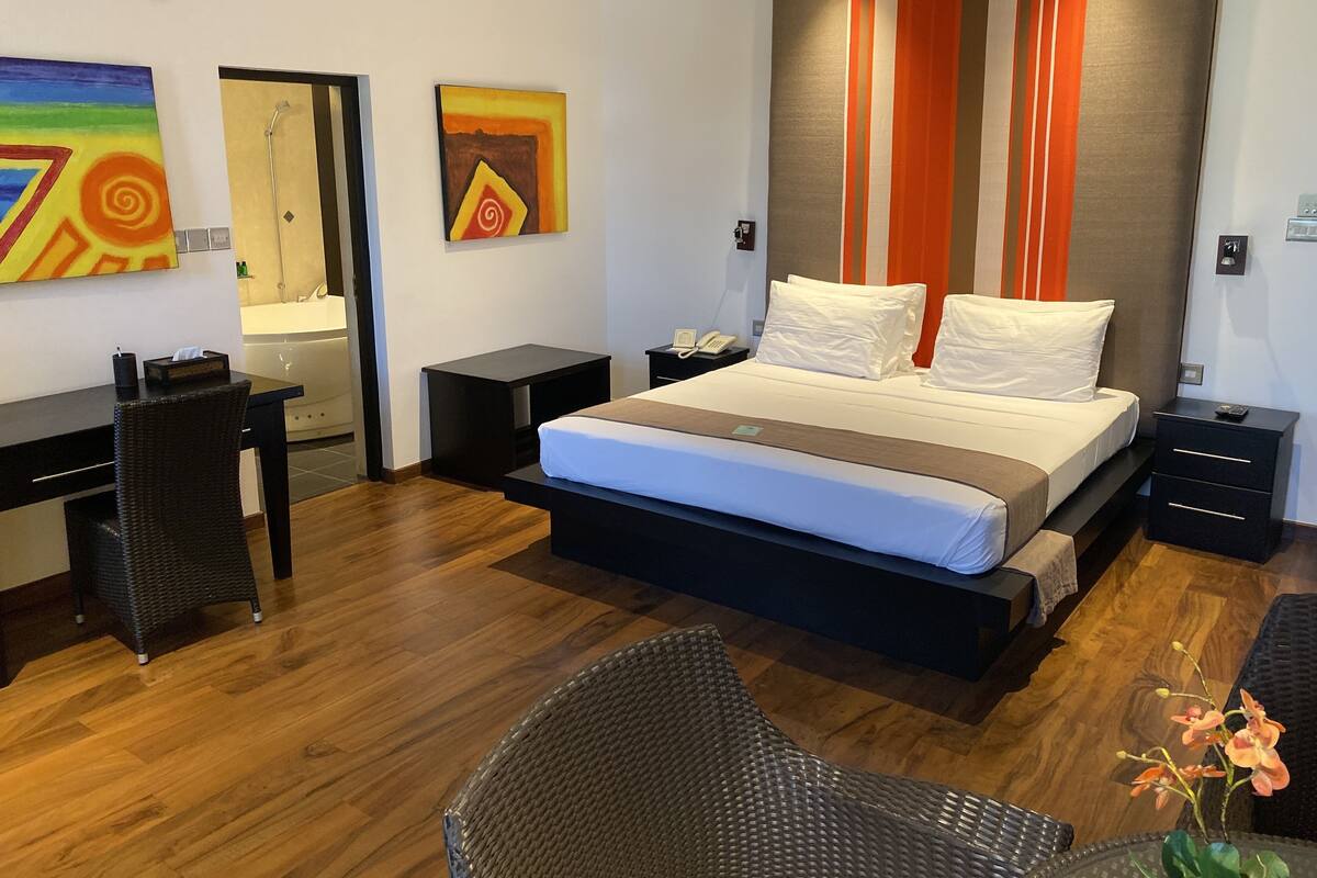 A modern hotel room with a large bed, a desk, a chair, and a bathroom.
