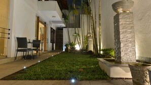 A courtyard with a dining area, potted plants, and a water feature. - D Villas (Sri Jayawardenepura Kotte)