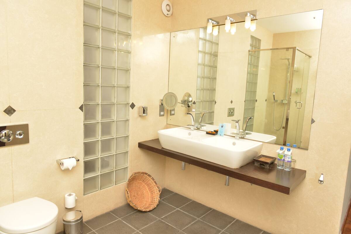A bathroom with a large mirror, a sink, a toilet, and a shower.