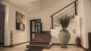 A modern interior with a wooden staircase, a large vase, and a painting on the wall. - D Villas (Sri Jayawardenepura Kotte)