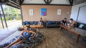 Un amplio espacio interior con suelo de madera, dos sofás, una mesa y un banco.