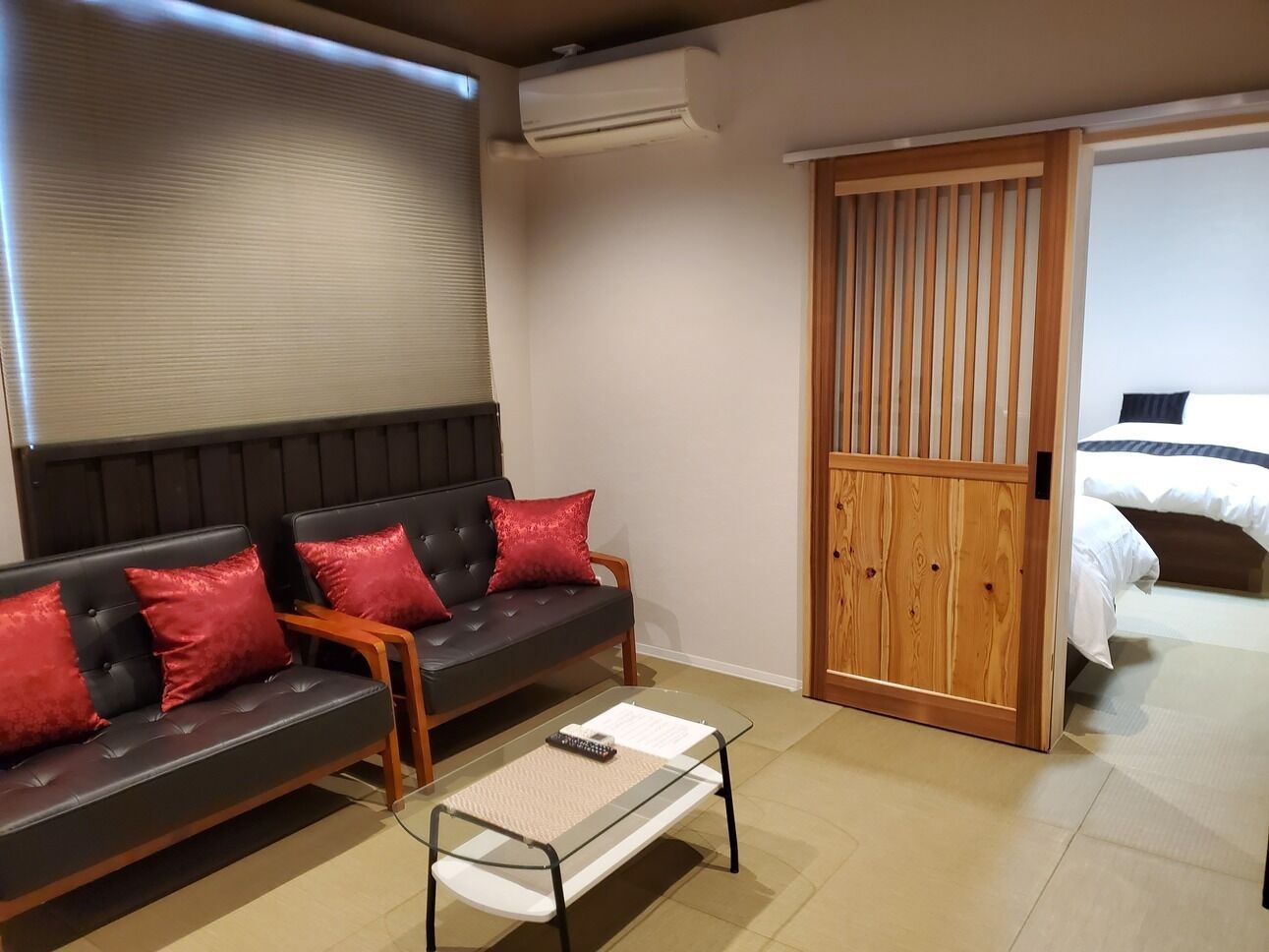 Um quarto com sofá, mesa de centro, porta deslizante e cama.