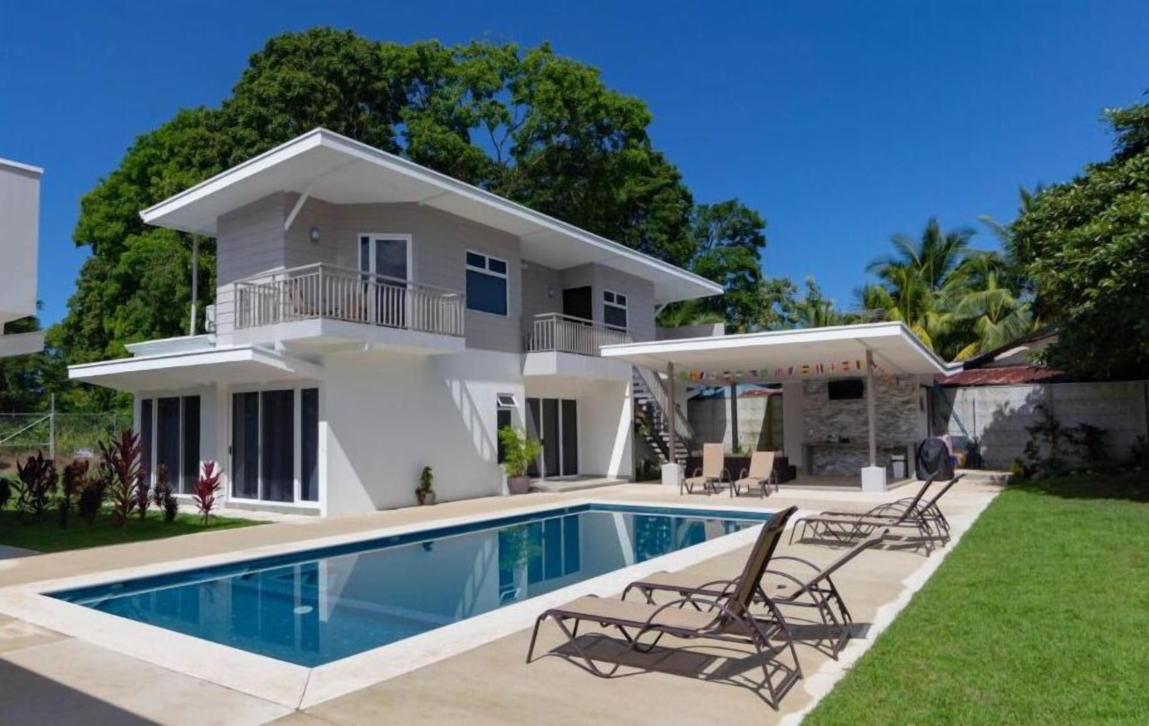 Une maison à deux étages dotée d’une piscine, d’un balcon et d’un espace extérieur couvert.