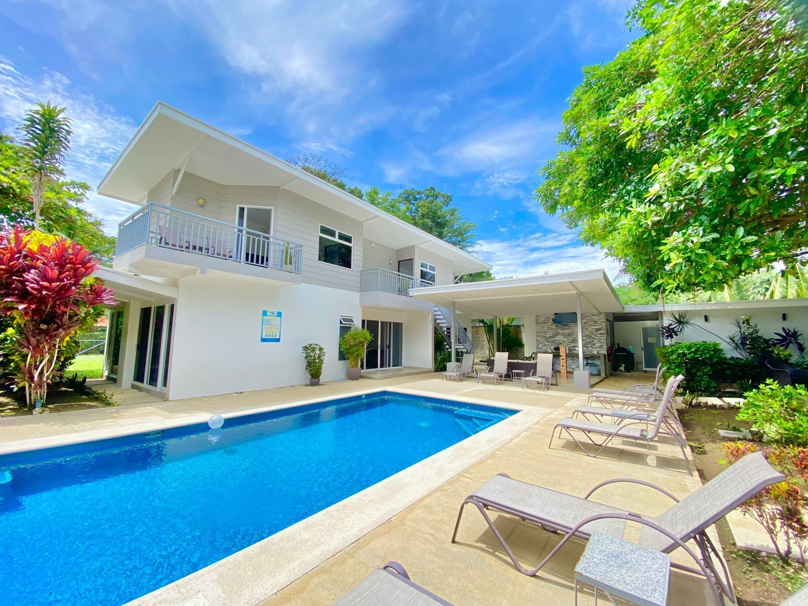 A two-story house with a swimming pool, outdoor seating, and a covered patio area.