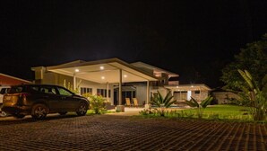 A modern house with a covered patio, a car parked in front, and a well-maintained lawn. - Uvita Paradise (Bahía Ballena)