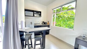 A modern kitchen with a built-in microwave, refrigerator, and sink. There is a window with a view of greenery outside. - Uvita Paradise (Bahía Ballena)