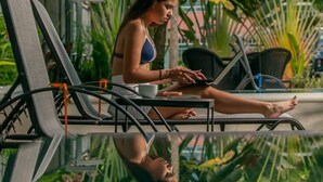 A person sitting on a lounge chair by a poolside, with lush greenery in the background. - Uvita Paradise (Bahía Ballena)
