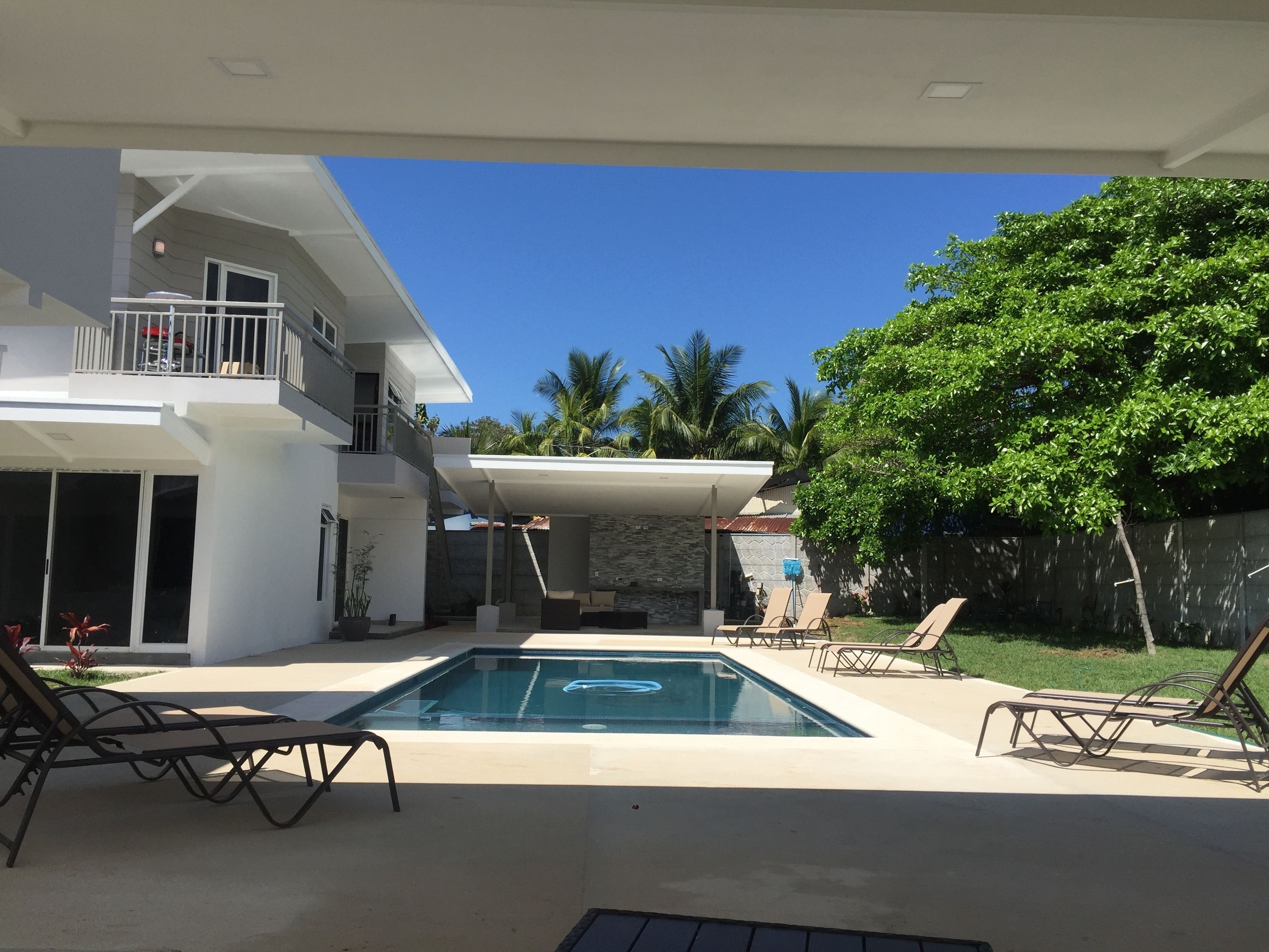A modern house with a swimming pool, outdoor seating, and a balcony.