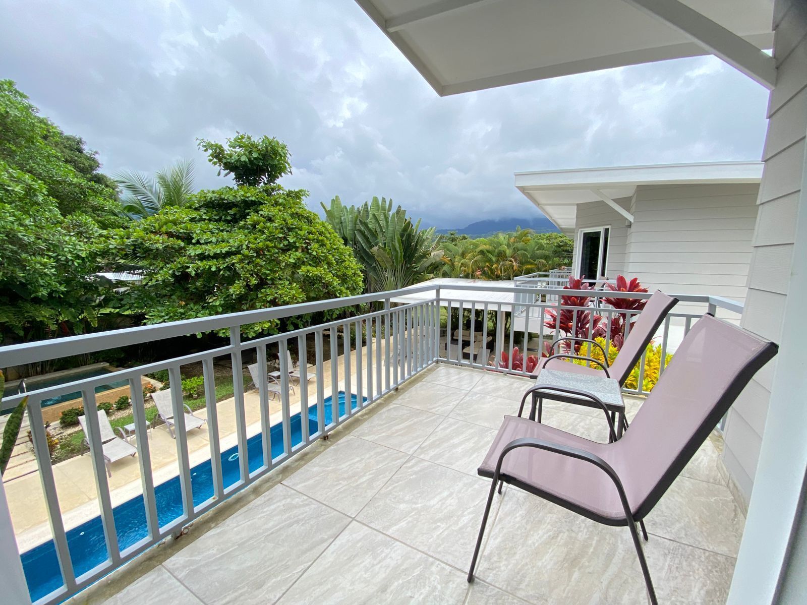 Un balcon avec une piscine, des chaises et une vue sur la verdure environnante.