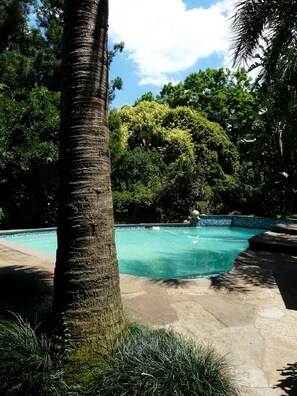 Una piscina al aire libre, sombrillas, sillones reclinables de piscina