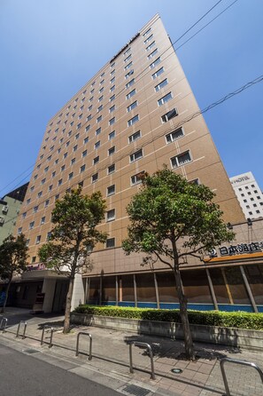 Un edificio de hotel alto con varios pisos, una entrada visible y un cartel que indica que es un hotel.