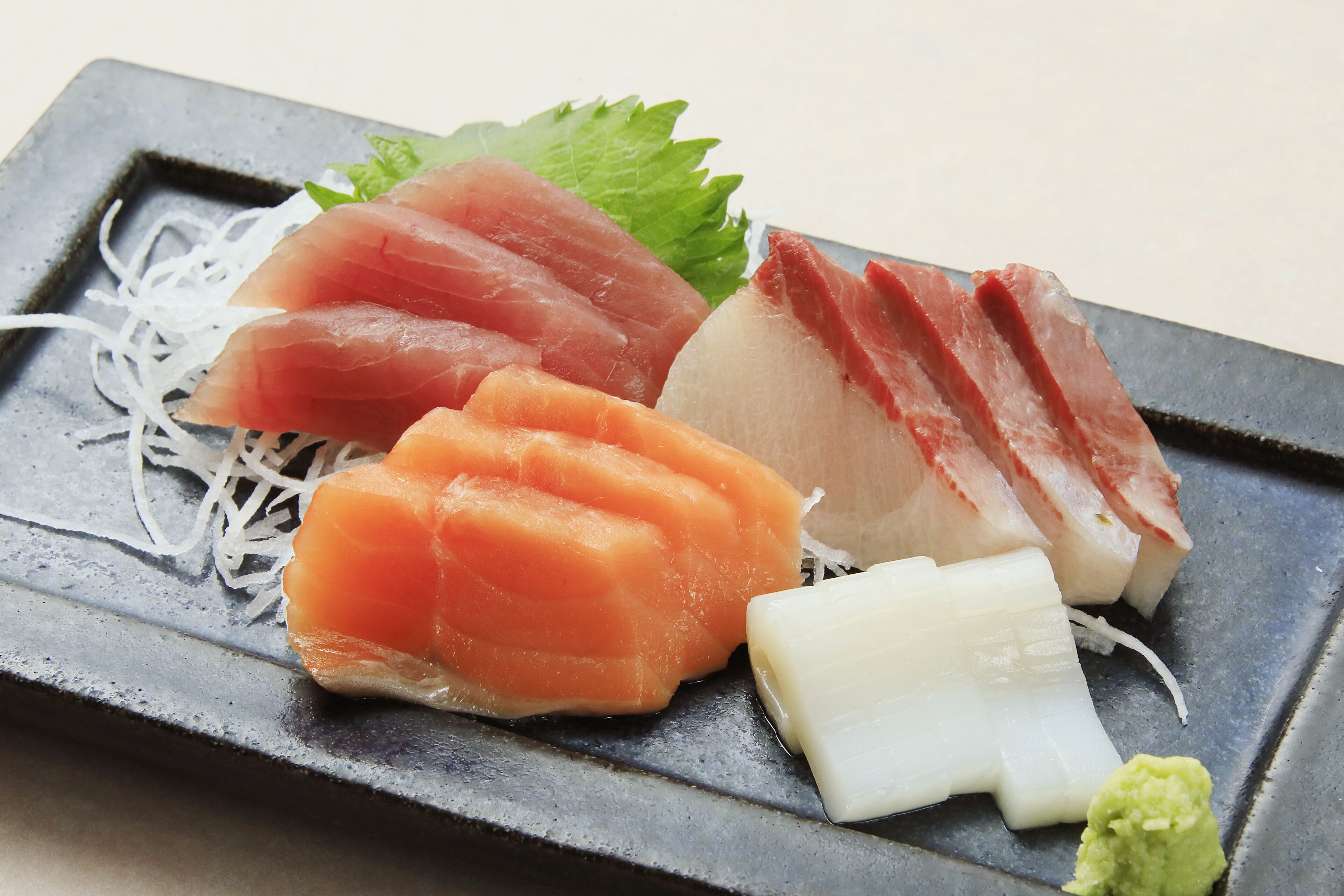 A variety of sushi on a rectangular plate with a dark background.
