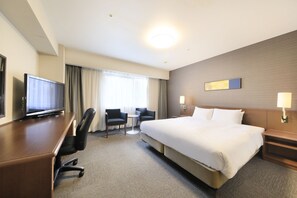 A hotel room with a large bed, a desk with a television, two armchairs, a small table, and a window with curtains. - Richmond Hotel Utsunomiya Ekimae (Utsunomiya)