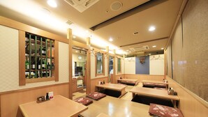 A restaurant with wooden tables and benches, a bar area with bottles, and a counter with a clock. - Richmond Hotel Utsunomiya Ekimae (Utsunomiya)