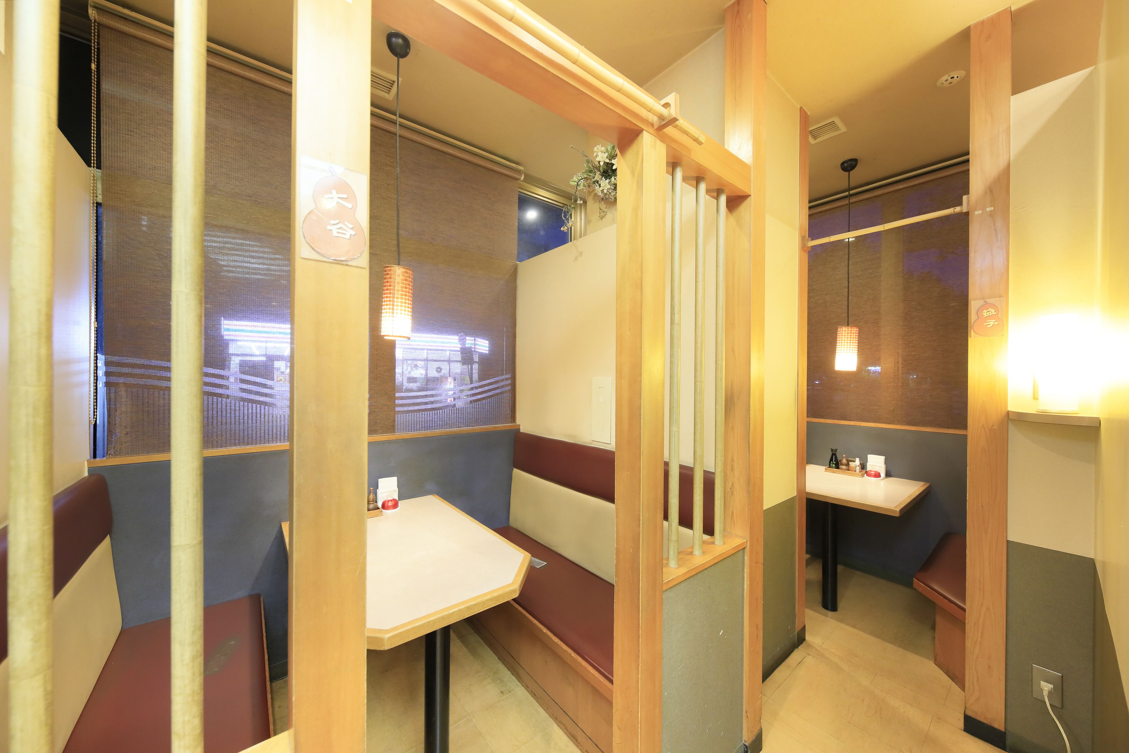 Un restaurante con cabinas, separadores de madera y lámparas colgantes.