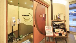 A hotel entrance with a wooden door, a signboard with operating hours, and a small outdoor area with plants. - Richmond Hotel Utsunomiya Ekimae (Utsunomiya)