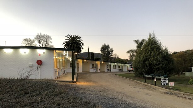 Un motel doté d’un espace extérieur abrité, d’une allée en gravier et d’un panneau indiquant la limite de vitesse, fixée à 5 km/h, pour les occupants.