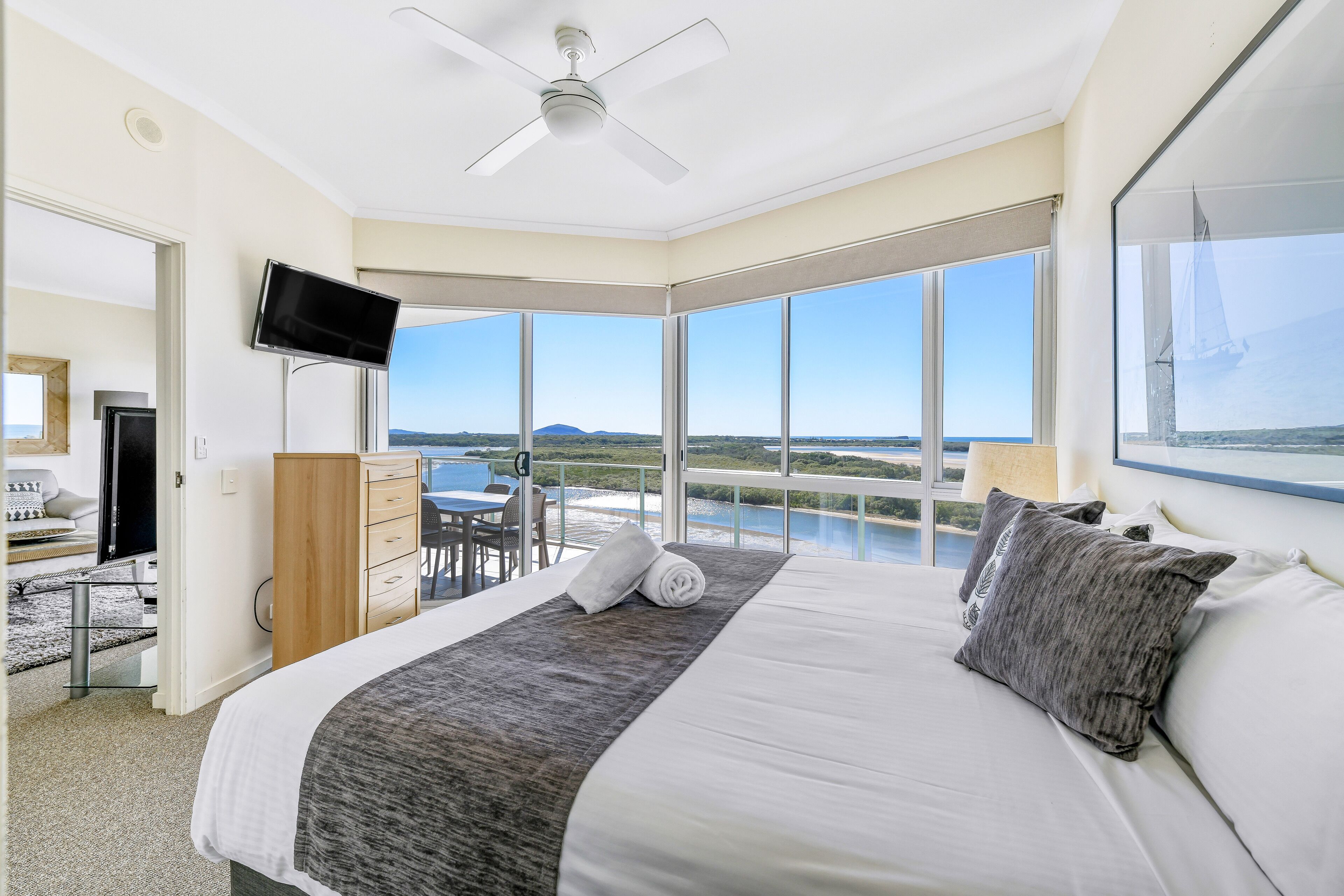 Ein modernes Hotelzimmer mit einem großen Bett, einem Deckenventilator, einem Flachbildfernseher und einem Balkon mit Meerblick.