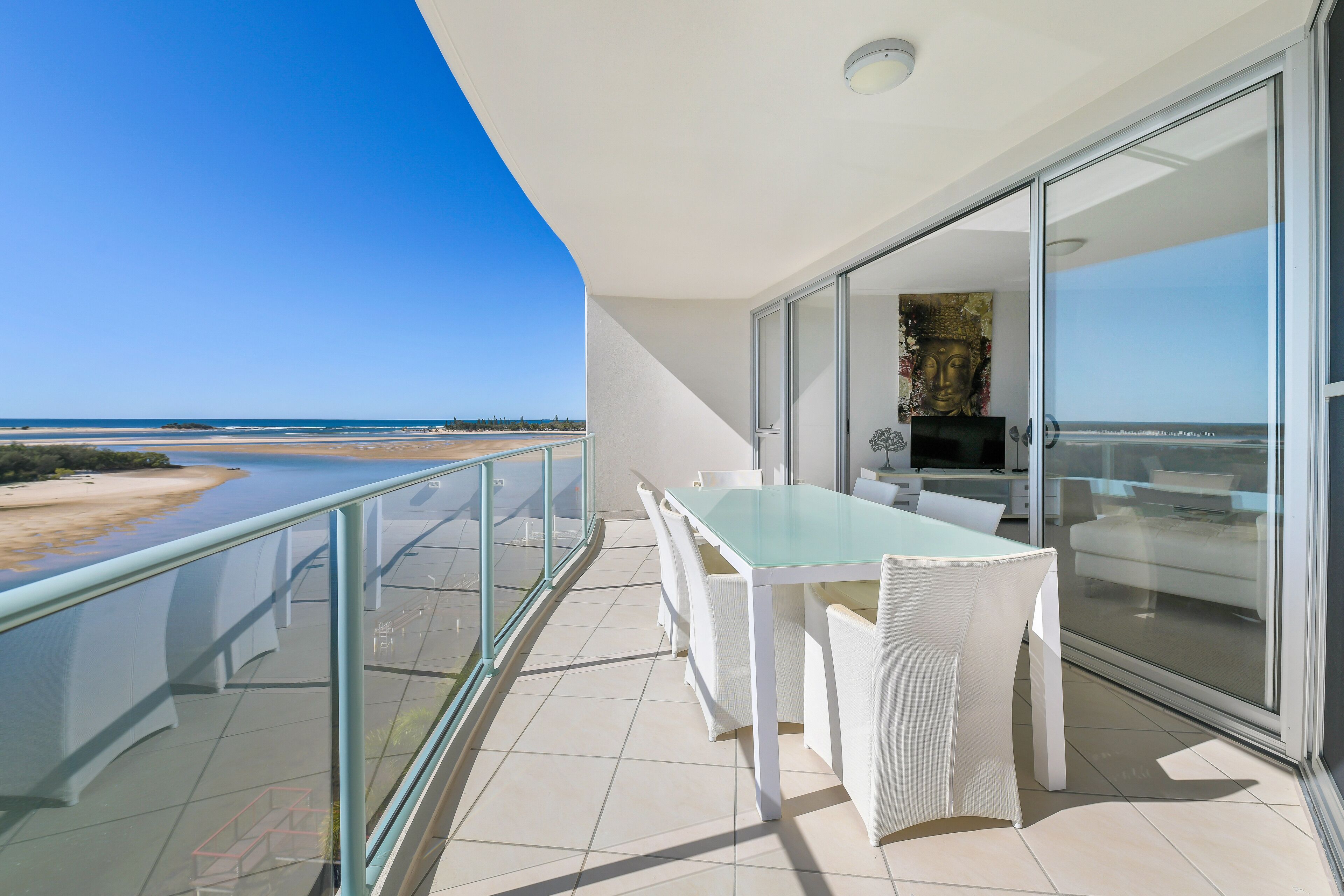 A balcony with a glass railing overlooking a beach.