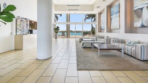A spacious lobby with a large seating area, a reception desk, and a view of the ocean. - The Duporth Riverside (Maroochydore)