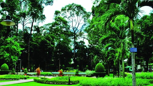Ein gepflegter Park mit ordentlich geschnittenen Rasenflächen, verschiedenen Bäumen und einem klaren Weg.