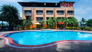 Una piscina rodeada de palmeras y un edificio con el letrero 'MGM'.