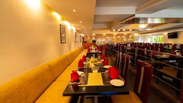 Un restaurante con mesas comunitarias largas, asientos acolchados y un interior cálido y bien iluminado.