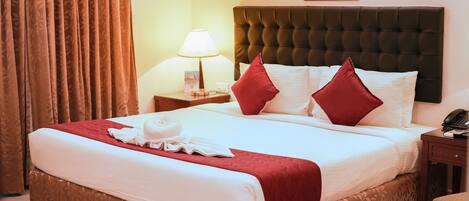 A neatly made bed with a red and white bedspread, a brown headboard, and a bedside lamp.