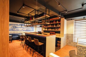 Un espace bar avec un comptoir, des tabourets et des étagères remplies de bouteilles.