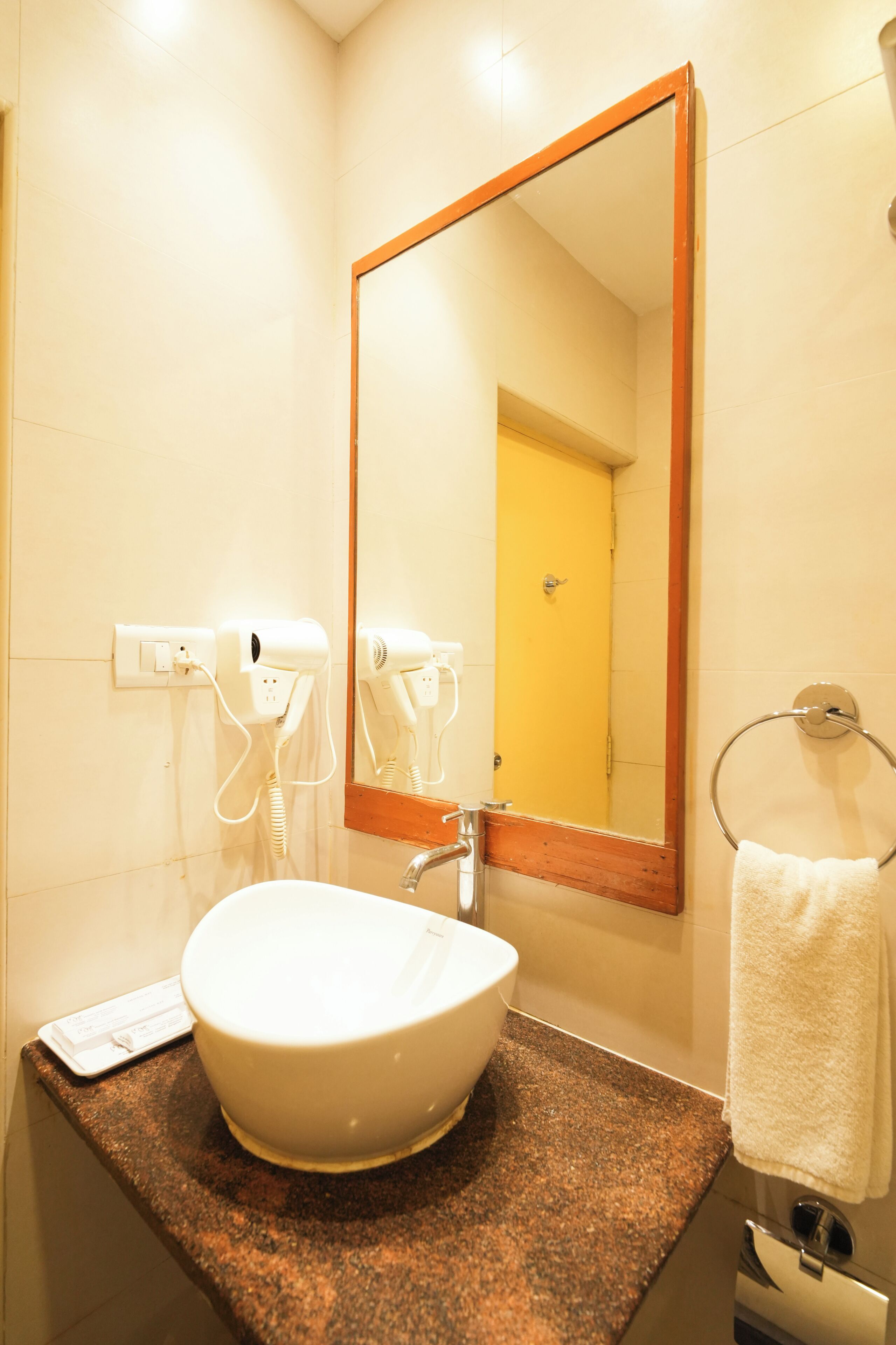 A bathroom with a sink, mirror, hairdryer, and towel rack.