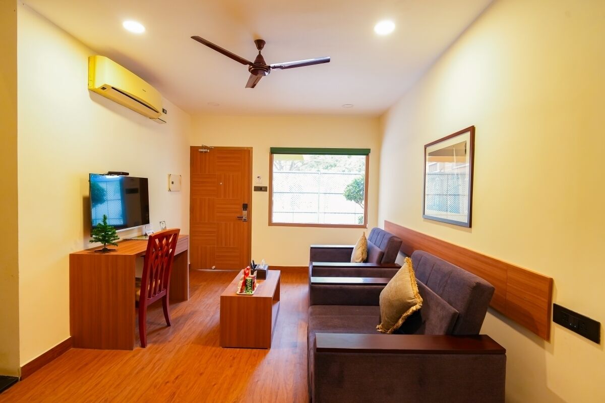 A modern living room with a sofa, a TV, a small table, and a ceiling fan.