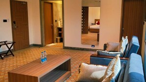 Habitación de hotel con sofá, una mesita de centro, un espejo y vistas al baño.