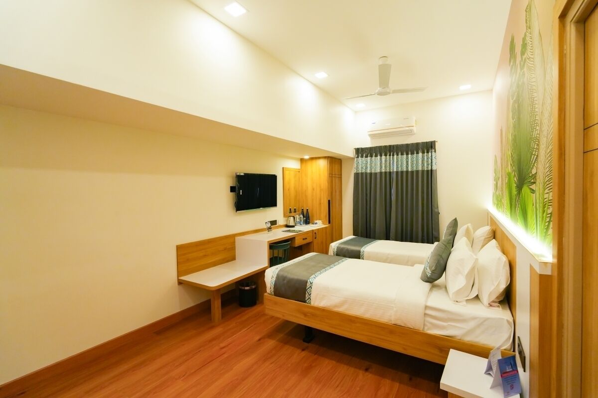 Una habitación de hotel con dos camas, un escritorio, un televisor y un ventilador de techo.