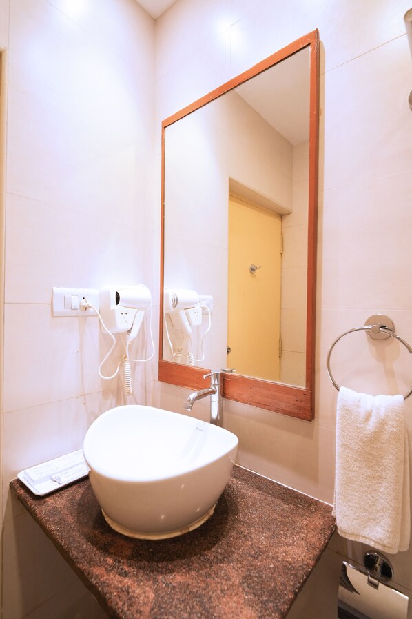 Un baño con lavamanos blanco, un espejo y un perchero para toallas.