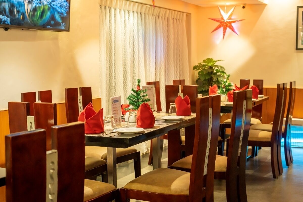 Un espace repas avec une longue table dressée pour accueillir plusieurs personnes, des chaises en bois et une étoile décorative accrochée au mur.