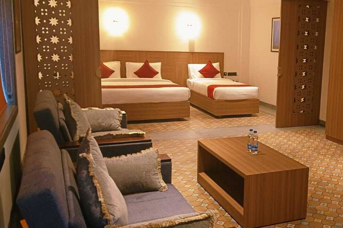 Ein Hotelzimmer mit zwei Betten, einem Sofa, einem Couchtisch, einem Fernseher und einem Schreibtisch.