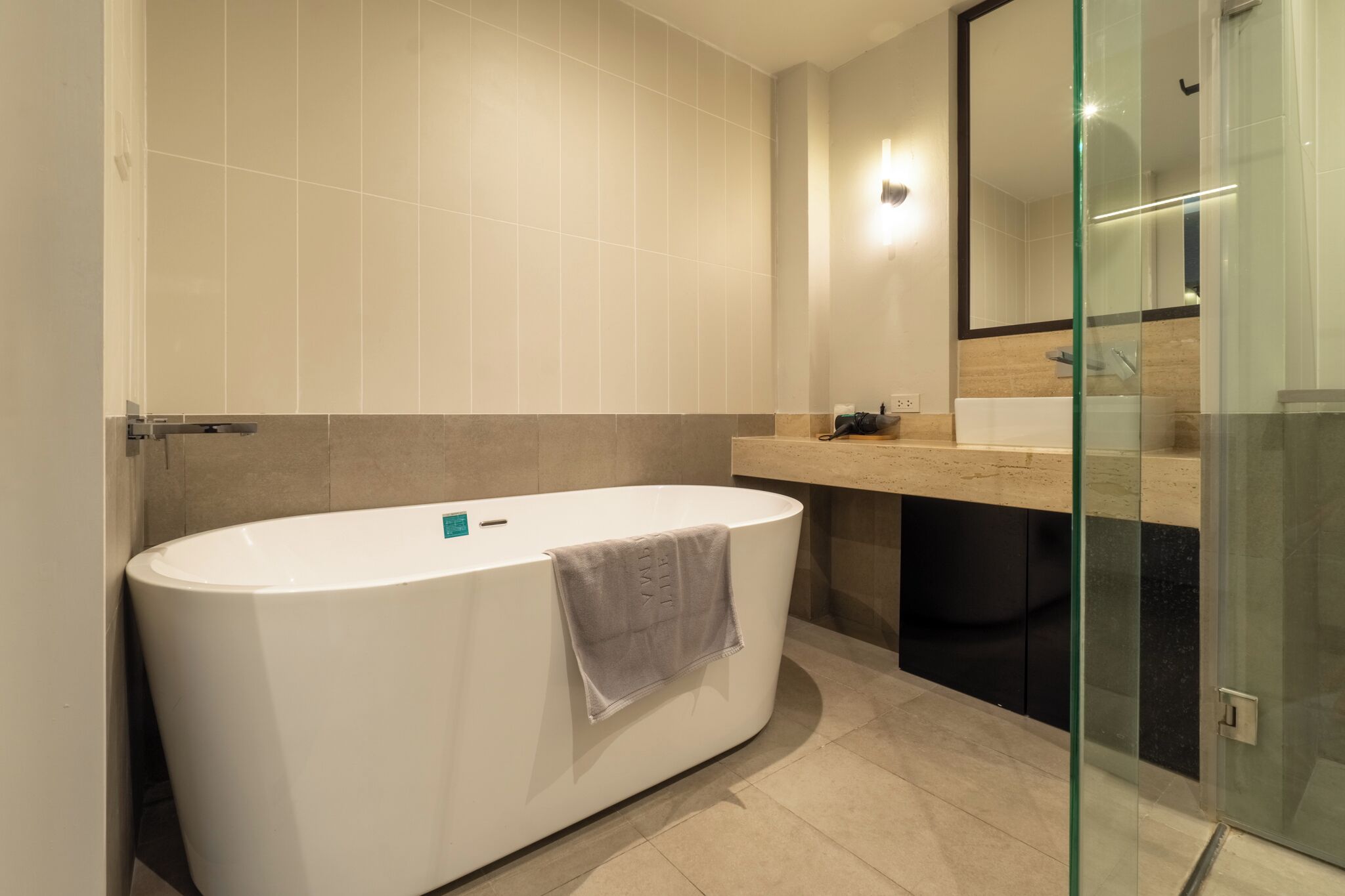 A modern bathroom with a freestanding bathtub, a glass shower enclosure, and a large mirror.