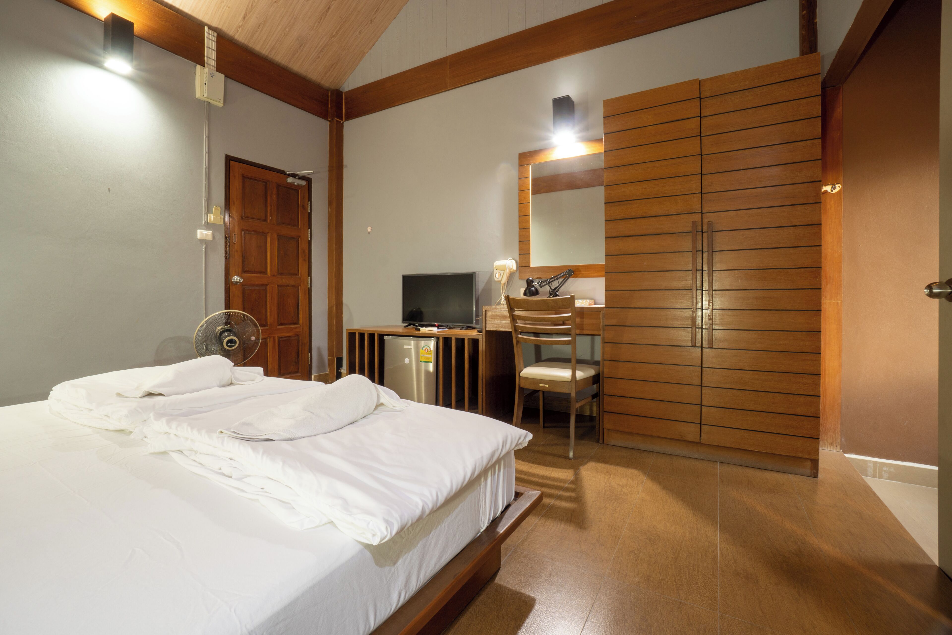 Un dormitorio con cama, escritorio, silla, armario y televisor.