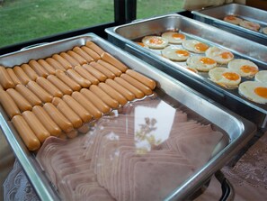 A buffet with hot dogs, eggs, and sliced meats. - The Grace Amphawa Resort (Samut Songkhram)
