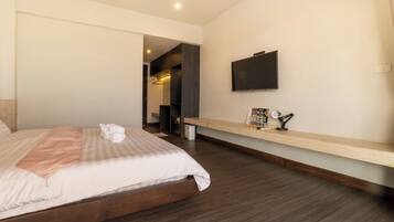 A modern hotel room with a large bed, a TV mounted on the wall, and a wooden floor.