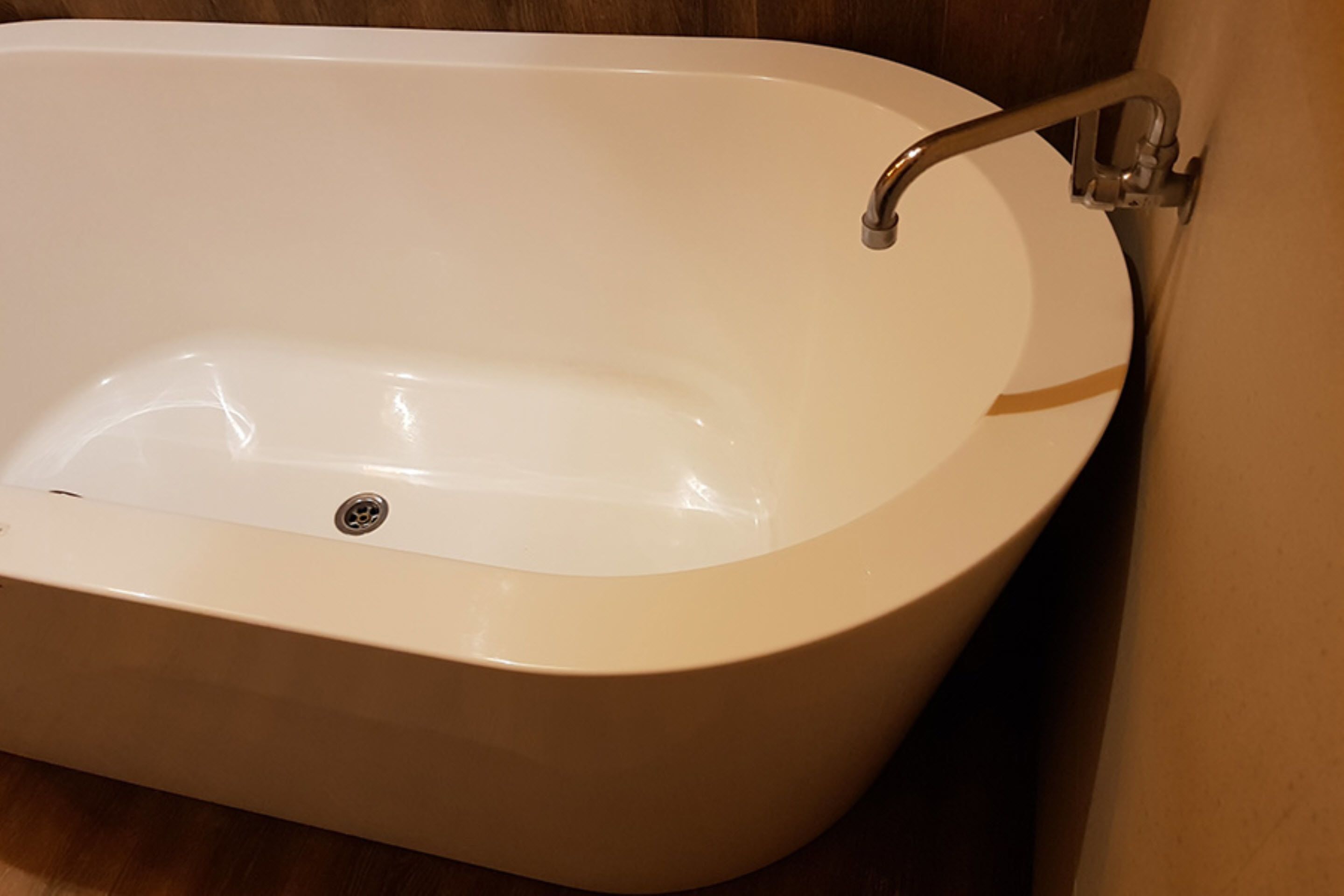 Una bañera blanca con un solo grifo y desagüe.