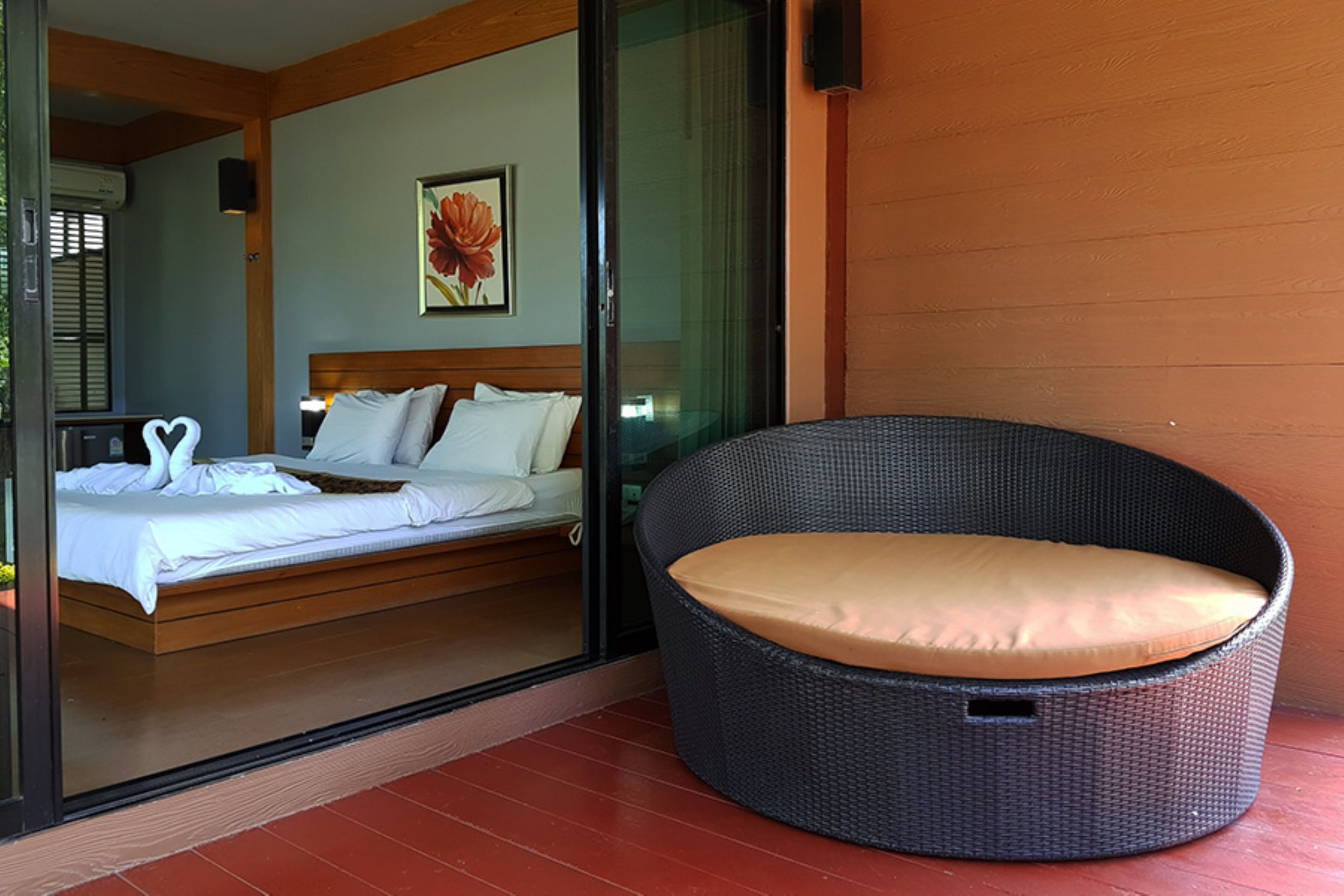 A bedroom with a bed, a wicker chair, and a glass door leading to another room.