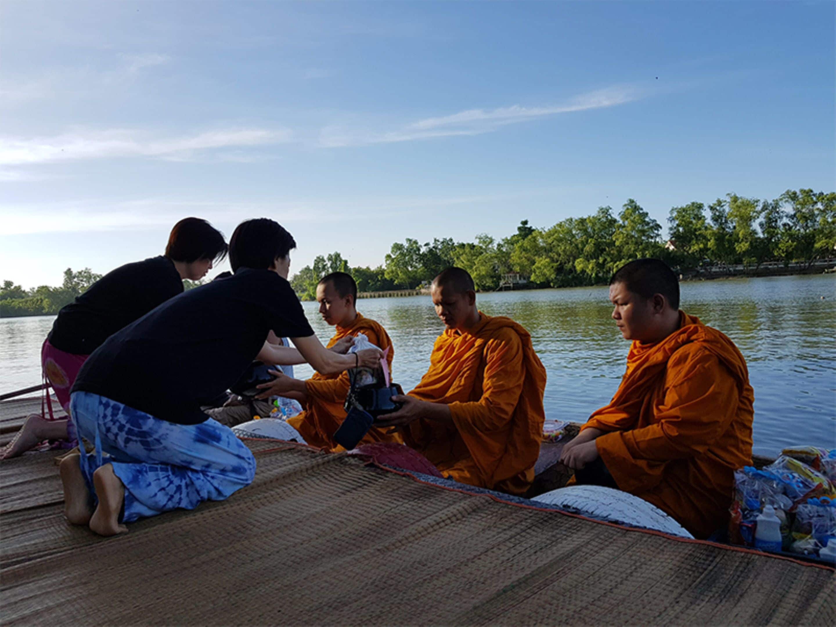 A group of people on a boat with a calm river and trees in the background.
