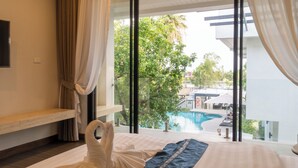 Habitación de hotel con cama, vista a una piscina y balcón.