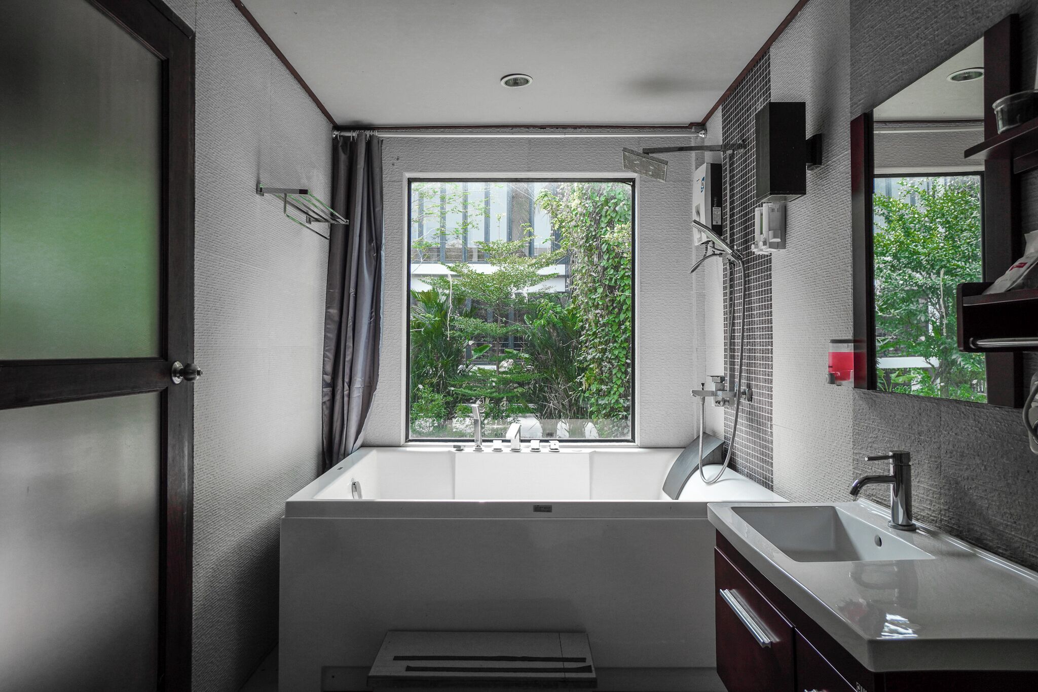 Un baño moderno con un ventanal grande, una bañera, un lavamanos y un espejo.