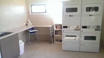 A compact kitchen with a sink, a small dining table, a baby high chair, and a built-in oven.