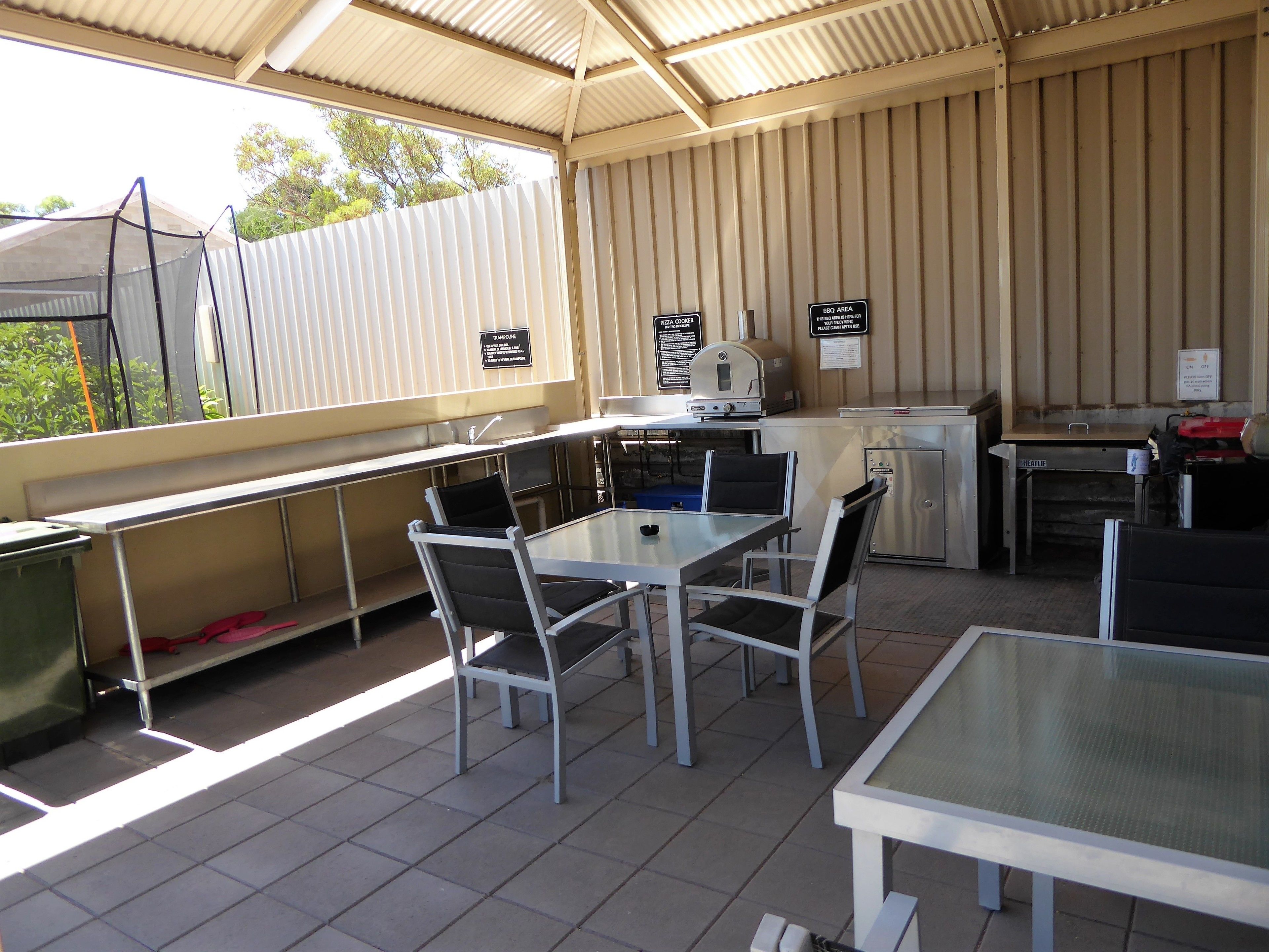Un espacio al aire libre con patio, mesa, sillas, una parrilla y un refrigerador.