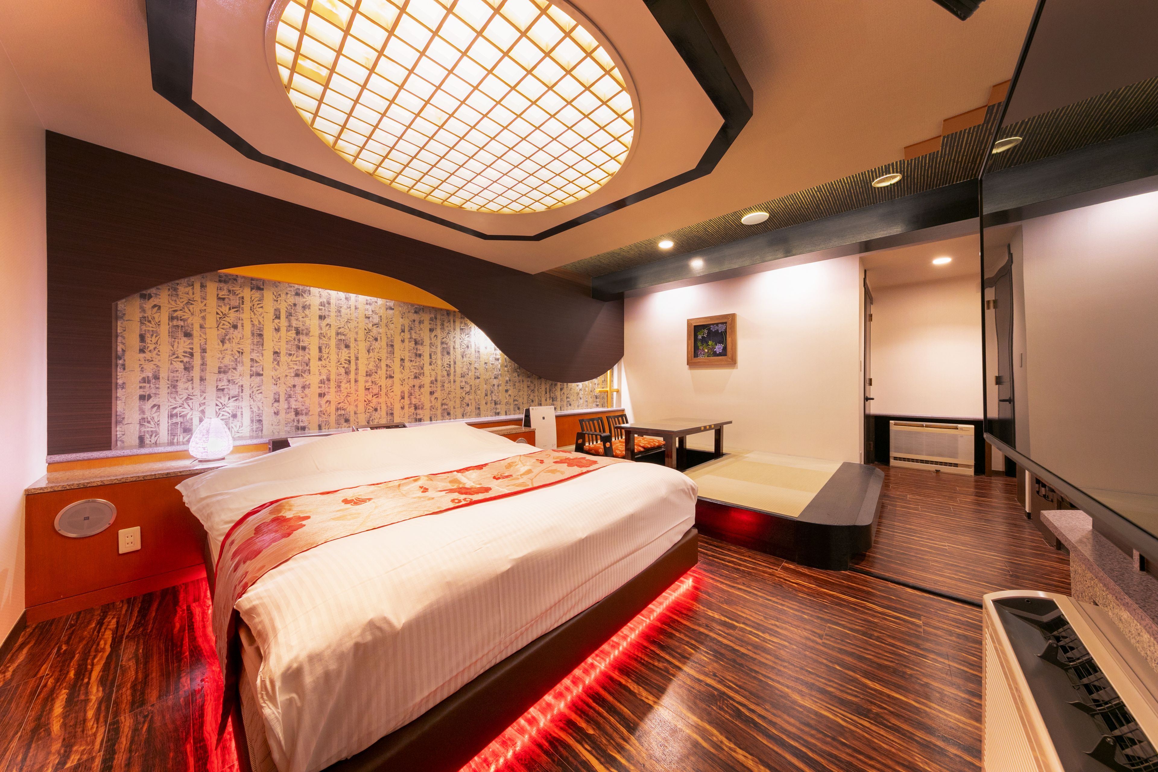 A modern hotel room with a large bed, a desk, and a seating area.